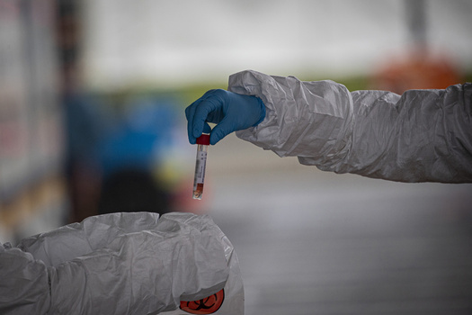 Documenting the pandemic at test centres. Medical staff holding a sample of blood in a vial.