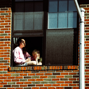 Two people sit on their window sill in Brooklyn for the Come To My Window during COVID-19