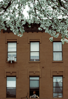 A young woman sits on her Brooklyn window sill for the Come To My Window project