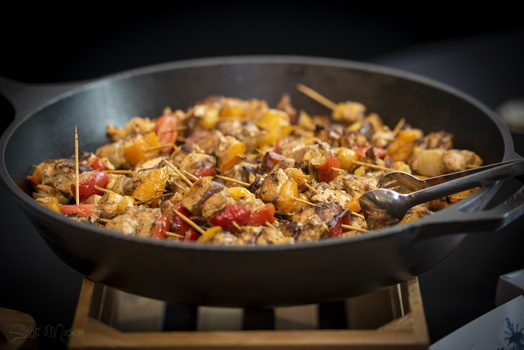 a cast iron skillet with kebabs cooking on it