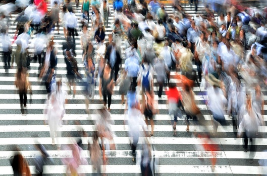 people walking in a blurred image on a sidewalk