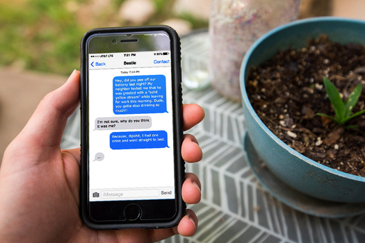 a hand holding an iPhone with a private text conversation on it