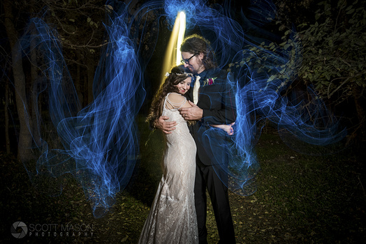 a wedding couple in the woods at night with blue lights surrounding them