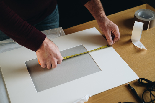 Designing and printing your photographs. A man measuring a photo mount.