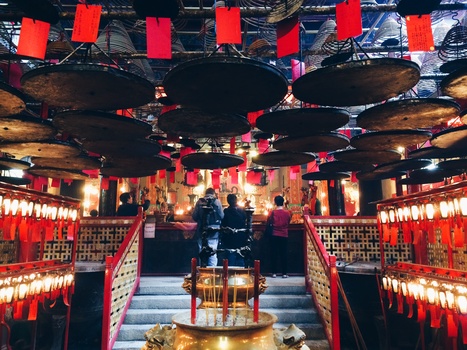 Red lanterns and warm lighting fill a symmetrical temple interior with central altar and stepped entrance.