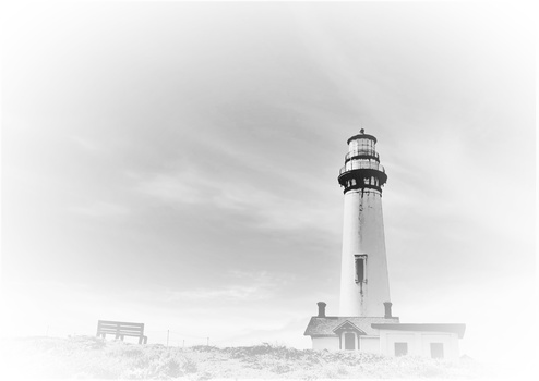 Tall lighthouse with attached keeper's house under overcast sky in black and white.