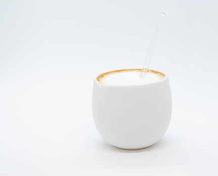 White ceramic vessel with gold-rimmed opening against neutral background.