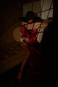 Silhouetted figure in red dress and black hat against dramatic window light with geometric shadows.