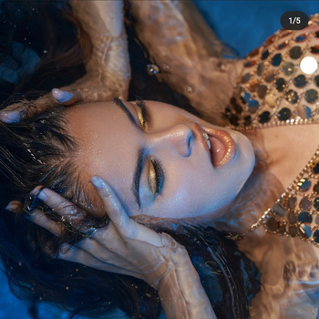 Woman's face underwater with gold eyeshadow and bronze leopard print fabric beside her.