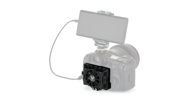 Black cooling fan with white logo mounted on camera body with monitor and cable attached.