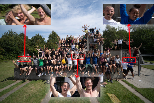 Large group photo of people arranged in rows on a grass field with a playground structure behind them.