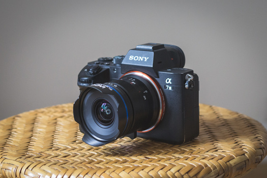 Sony Alpha a7 mirrorless camera with attached lens on woven straw surface.