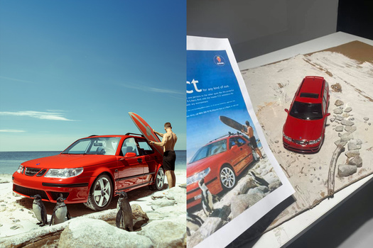 Red sedan at beach with open door and surboard, alongside product packaging and toy car model on sand.
