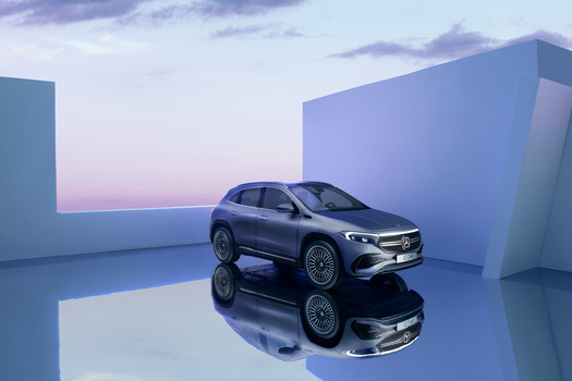 Silver SUV positioned between large blue geometric structures on a reflective white surface at dusk.