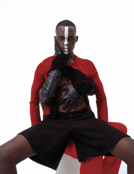 Male model in red and black athletic wear posed against white background.