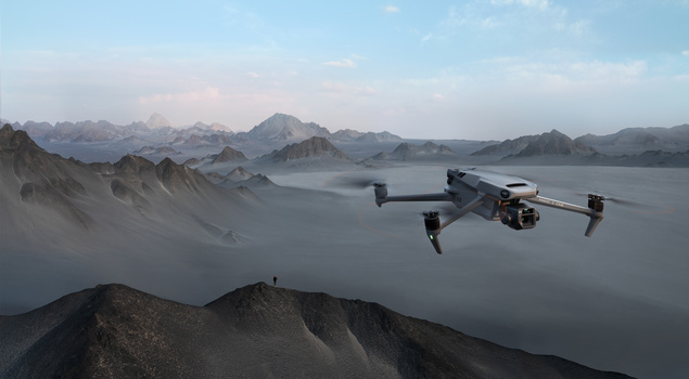 Drone hovering above a misty volcanic landscape with dark peaks and a gray lake.