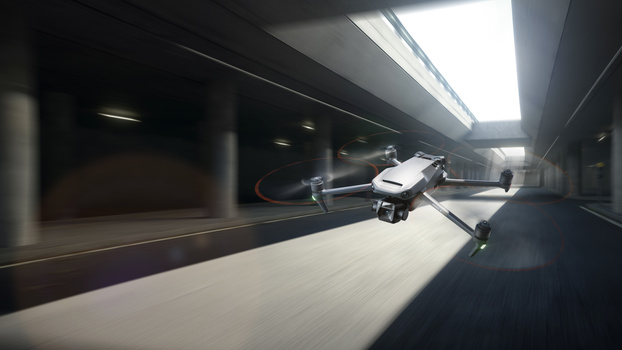 Drone in flight through a modern architectural corridor with linear ceiling lights and concrete surfaces.