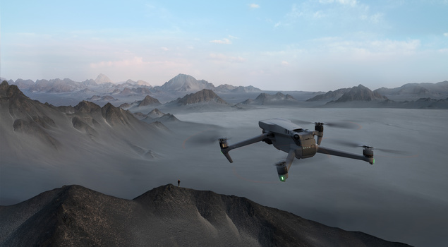 Drone flying above a misty mountainous landscape with jagged peaks and fog-filled valleys.