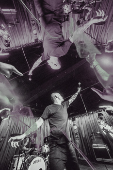 Drummer performing energetically with overhead view of drum kit and cymbals in black and white.