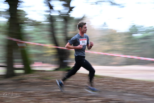 Runner crossing finish line with motion blur effect during outdoor race event.