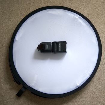 Two wireless camera flash triggers positioned on a white circular light reflector.