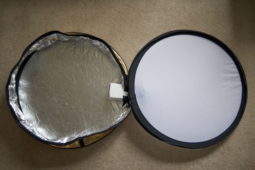 Two circular reflectors with black frames, one showing silver crinkled surface and one showing white diffusion material.