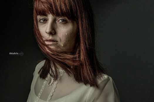 Portrait of a woman with reddish-brown hair against dark background, lit with dramatic side lighting.
