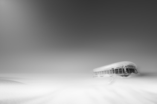 Snow-covered structure emerging from a dense winter landscape in monochrome.