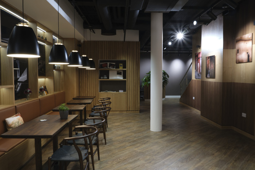 Modern interior space with wooden dining table, pendant lighting, and gallery walls in warm and cool tones.