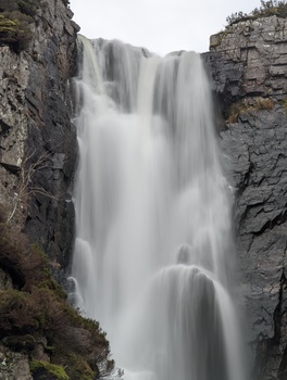 Waterfall cascading between two rocky cliff faces with silky, flowing water effect.