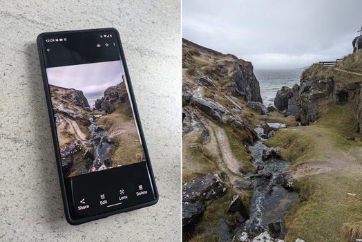 Smartphone displaying a landscape photograph of a rocky coastal stream valley alongside the full scene photographed outdoors.