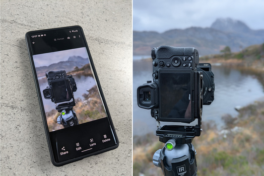 Mobile phone displaying a large format camera mounted on a tripod overlooking a mountain landscape.