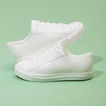 Pair of white canvas low-top sneakers with checkered heel detail on mint green background.