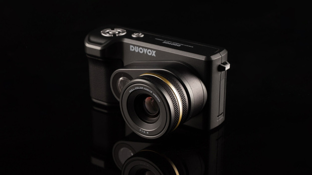 Duovox camera with prominent lens against black background with reflection.