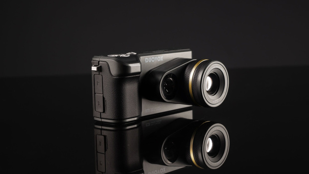 Photon camera with prime lens against black background with mirror reflection below.