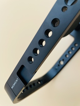 Close-up of a dark blue camera strap with evenly spaced ventilation holes and branded text.