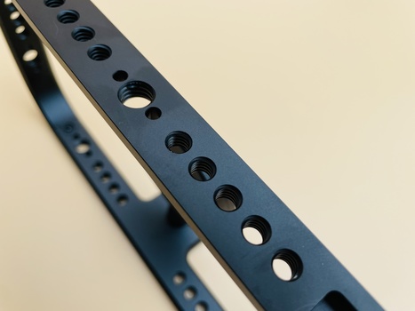 Close-up of a dark blue metal strap or belt with evenly spaced round holes running along its length.