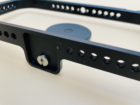 Black perforated camera strap with adjustment mechanisms and a blue rubber grip pad.
