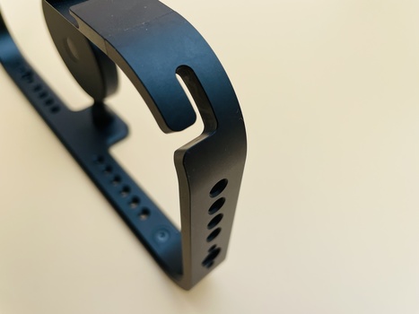 Close-up of a blue fitness tracker band with white trim and black clasp against a light background.