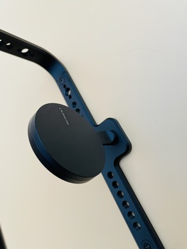 Blue and black sports watch with adjustable band against neutral background.