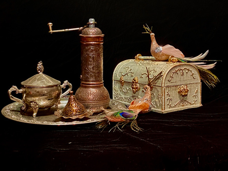 Ornate brass and copper decorative objects arranged on black surface with bird figurines.