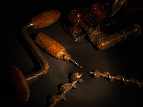 Vintage woodworking and metalworking hand tools arranged on dark surface with dramatic lighting.