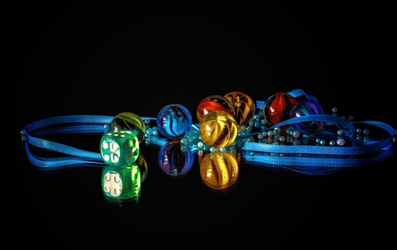 Colorful illuminated polyhedral dice arranged on blue ribbons against a black background.