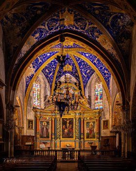 Ornate cathedral interior with blue and gold vaulted ceiling, central gilded altar, and symmetrical side chapels.