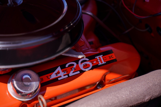Close-up of a 426 engine badge on a bright orange automotive engine block with visible cooling components.