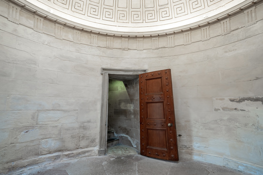 Empty circular room with geometric ceiling pattern and open wooden door.