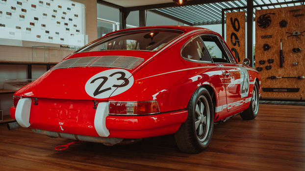 Red vintage race car with number 23 displayed on hood and door, shown in museum or gallery setting.