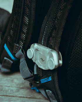 Close-up of a camera trigger mechanism mounted on a rifle scope rail with blue accents.