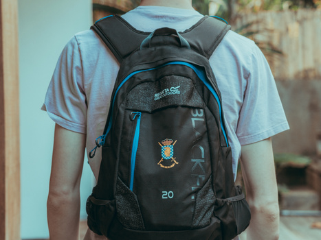 Person wearing a black and blue backpack with a crest emblem and number 20 on the back pocket.