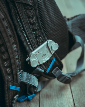 Close-up of a camera mounted on a backpack shoulder strap with blue accents.